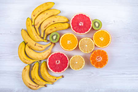 Sliced citrus fruits with bananas top view on white backgroundの写真素材