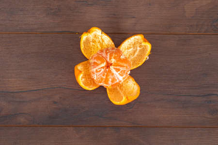 Fresh peeled mandarin isolated on brown background with copy space