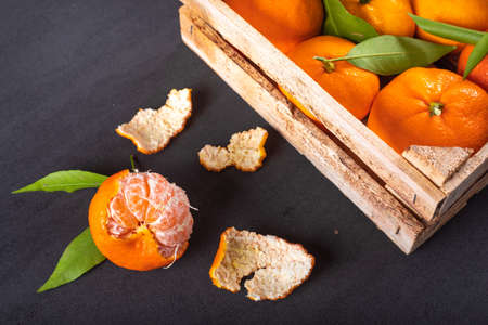 Fresh mandarins in wooden box on black tableの写真素材