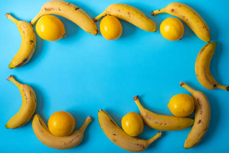 Top view bananas and lemons arranged as frame on blue backgroundの写真素材