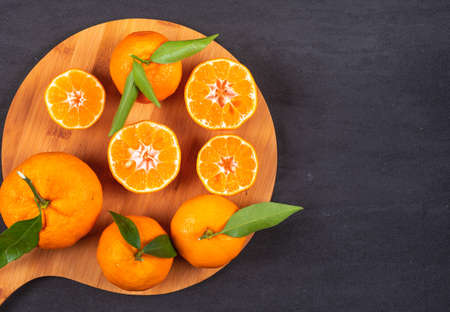 Mandarins top view on wood cutting board on black stone backgroundの写真素材