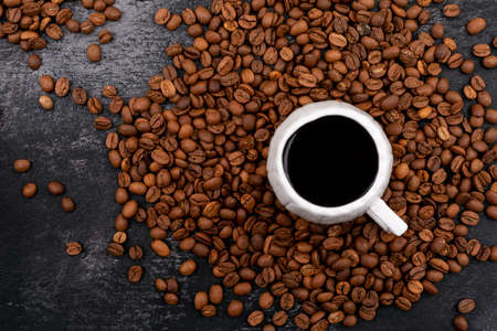 Cup of coffee surrounded with coffee beans on black background 1