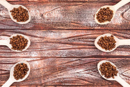 Coffee beans in wooden spoons with copy space on wooden backgroundの写真素材