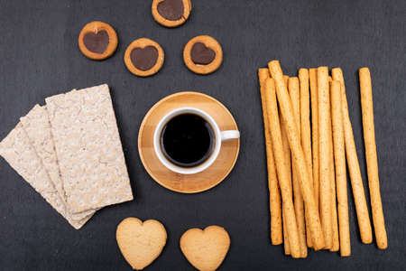 Top view different cookies and coffee cup on dark background