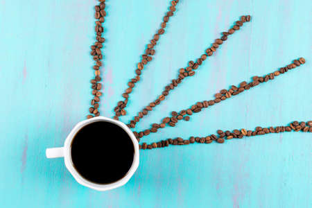 Top view coffee cup with coffee beans rays on blue tableの写真素材