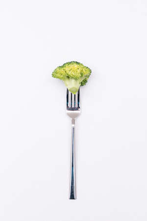 Piece of fresh broccoli on fork isolated on white backgroundの写真素材