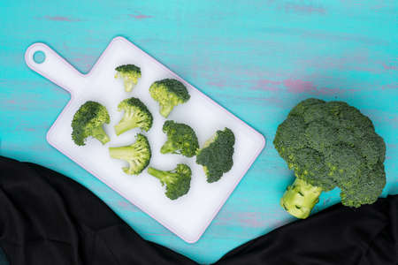 Top view cutting broccoli on white board on blue backgroundの写真素材
