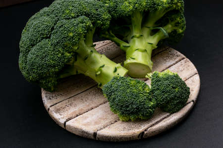 Fresh broccoli on cutting board on black background