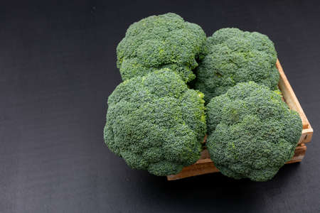 Fresh broccoli in wooden box on black background. green vegetables