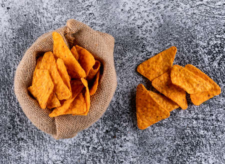 Top view chips in linen bag on white stone background horizontal