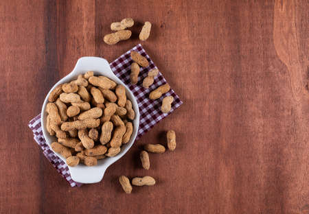 Top view raw peanuts in bowl on wooden background with copy spaceの写真素材