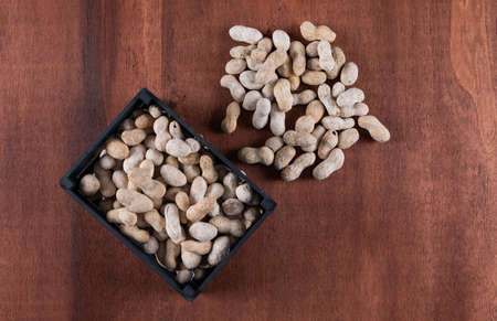 Side view peanuts in box on wooden brown background verticalの写真素材