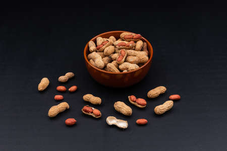 High angle view raw peanuts in bowl on dark background horizontal