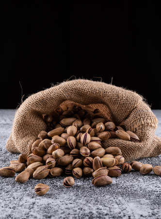 Side view pistachios in sack on gray texture background verticalの写真素材