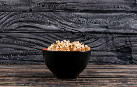 Side view of popcorn in bowl on dark wooden table horizontalの写真素材