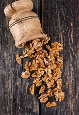 Top view walnuts in wooden mortar on wooden background vertical