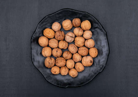 Top view walnuts in black plate on black background horizontal