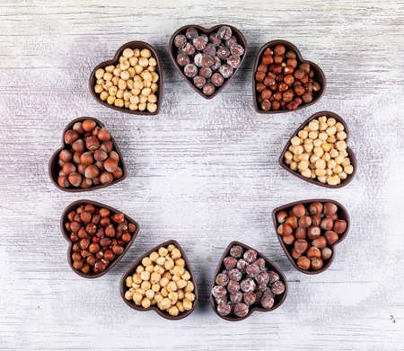 Set of shelled, cleaned hazelnuts and different hazelnuts in a heart shaped bowls on a white wooden background. top view. copy space for textの写真素材