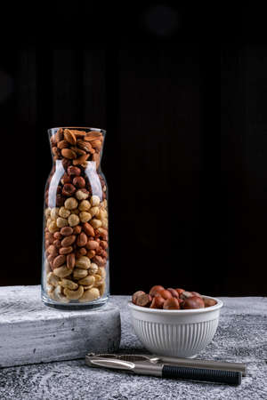 Top view different nuts in full bottle of nuts with bowl, cracker and pecan, pistachios, almond,...