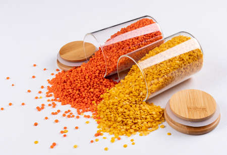 Yellow and red lentils in a glassy jar on a white background. side view. space for text