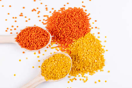 Yellow and red lentils in a wooden spoon on a white background. high angle view.の写真素材