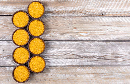 Yellow lentils in a brown bowls flat lay on a beige wooden background copy space for text