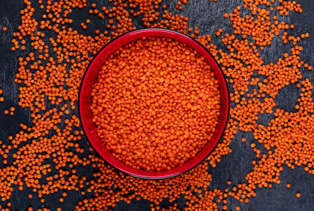 Top view red lentils in red bowl on dark stone background. horizontalの写真素材