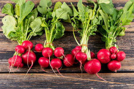 Fresh red radishes with some green fresh leafs high angle view on a wooden table background