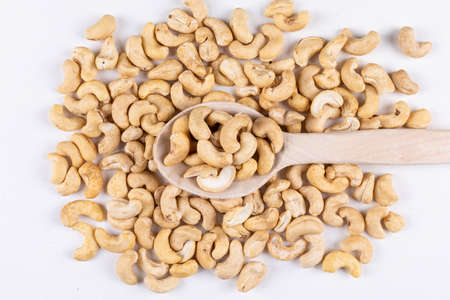 Scattered cashew in a wooden spoon on a white background. top view. の写真素材