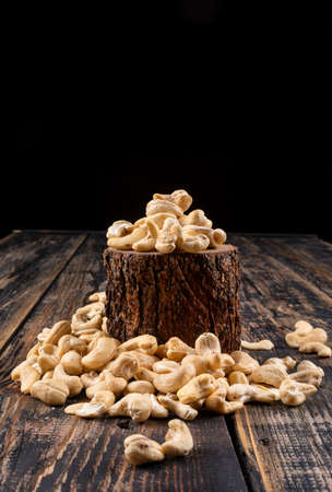 Different cashew with piece of wood on wooden textured background, side view. の写真素材