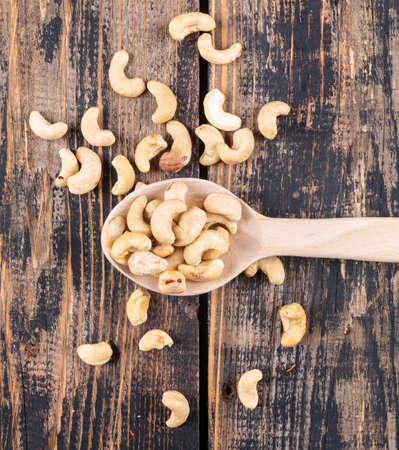 Top view cashews in wooden spoon on wooden texture background. verticalの写真素材
