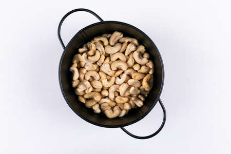 Cashew in a black pan top view on a white backgroundの写真素材