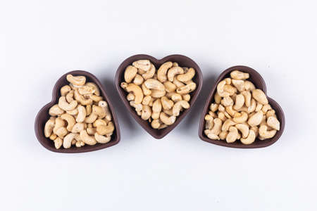 Cashew in a three heart shaped bowl on a white background. top view.の写真素材