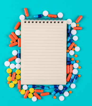 Close-up view notepad with pills on cyan blue background. horizontal space for textの写真素材