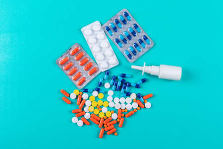 Flat lay colorful pills with nasal spray on cyan blue background. horizontal