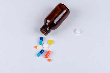 Colorful pills with pill bottle top view on a white background