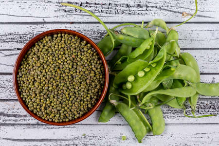 Peeled peas in a bowl and aside flat lay on a gray wooden background の写真素材