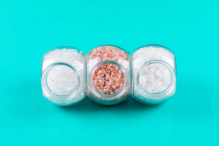 Top view sea salt in small jars with himalayan salt on cyan blue background. horizontal