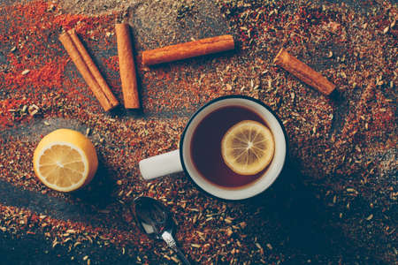 Top view lemon tea and dried herbs with dry cinnamon, spoon and lemon on dark background. horizontalの写真素材