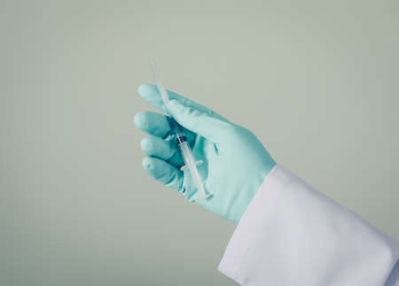 Side view doctor with gloves holding syringe in his hand on gray background. horizontalの写真素材