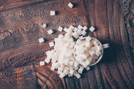 Flat lay white sugar cubes in cup on dark wooden background. horizontalの写真素材