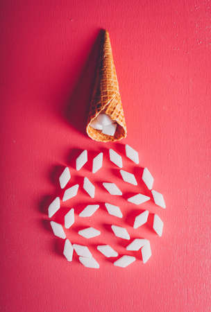 White sugar in ice cream waffle on a pink red background. top view.