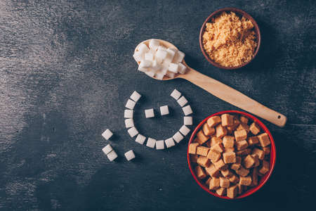 White sugar and emoji in bowls with spoon flat lay on a dark backgroundの写真素材