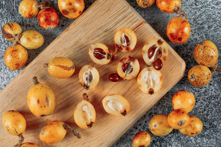 Top view loquats in cutting board on gray textured background. horizontal
