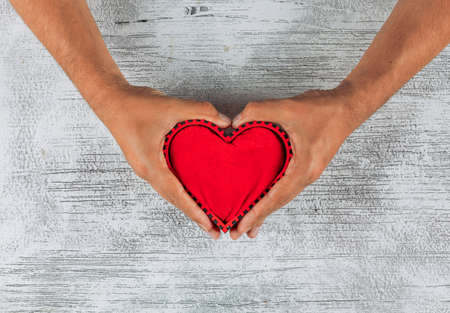Top view man holding heart shape with his hands on light wooden background. horizontalの写真素材