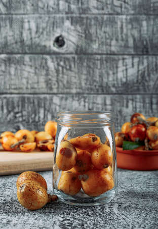 Side view loquats in jar on gray textured background. vertical, space for text