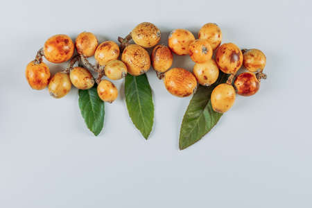Some loquats with leaves on white background, top view. space for text