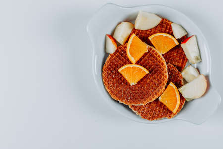 Some waffles with oranges and apples in a bowl on white background, top view. space for textの写真素材