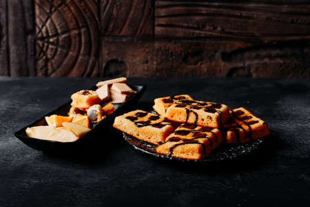 High angle view waffles in plate with cookies, orange on black textured and wooden background. horizontalの写真素材