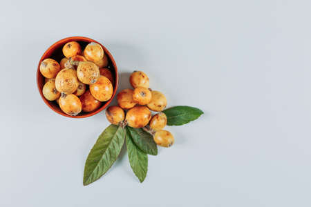 Set of leaves and loquats in a bowl on a white background. top view. space for textの写真素材
